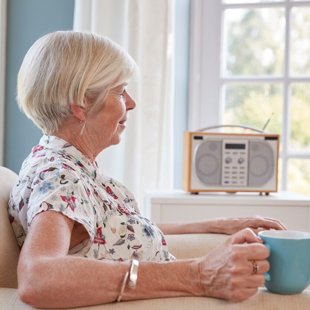 Senior woman drinking tea and listening to radio at home